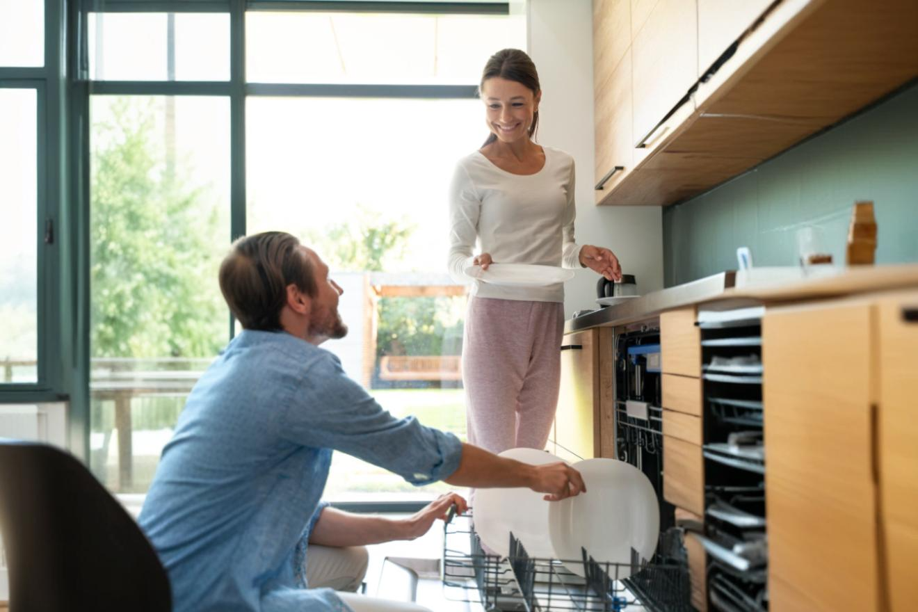 Smiling couple discuss dishwasher stacking